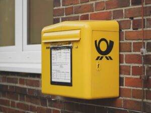 A yellow mailbox on a brick wall, as an example of who to notify when moving home.